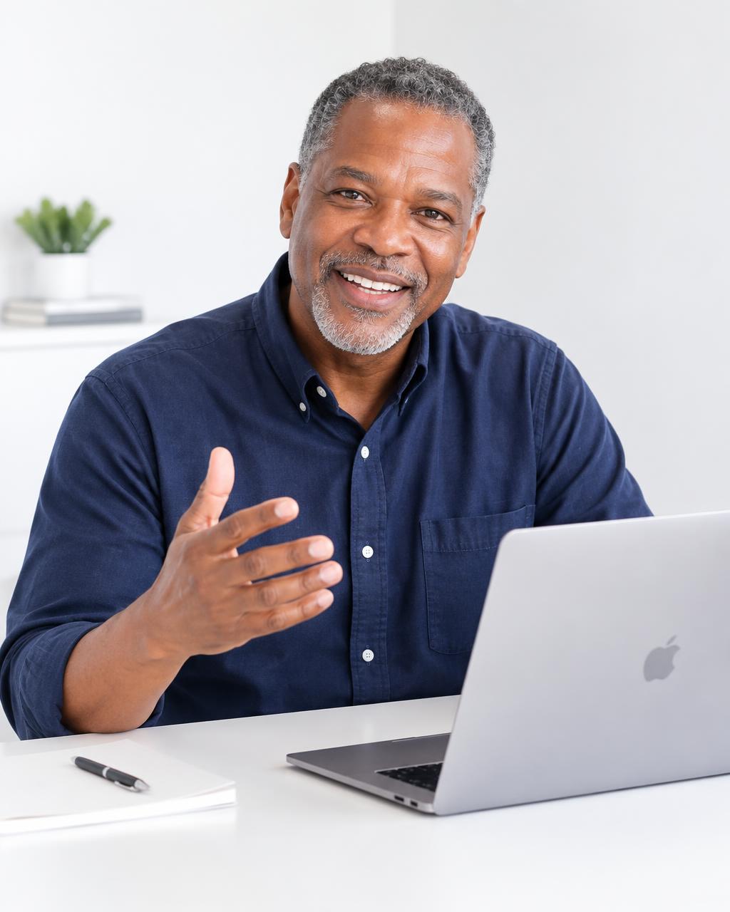 Friendly experienced computer instructor smiling at his desk with a laptop